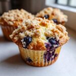 Close-up of a freshly baked blueberry muffin topped with golden brown streusel crumbs.