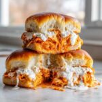 Two stacked buffalo chicken sliders overflowing with orange sauce and creamy ranch dressing on soft brioche buns.