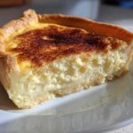 A close-up slice of amazing custard pie showing the thick, creamy filling and a golden, caramelized top.