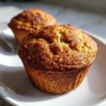 Close-up of a freshly baked banana protein muffin with a rich, cinnamon-dusted top.