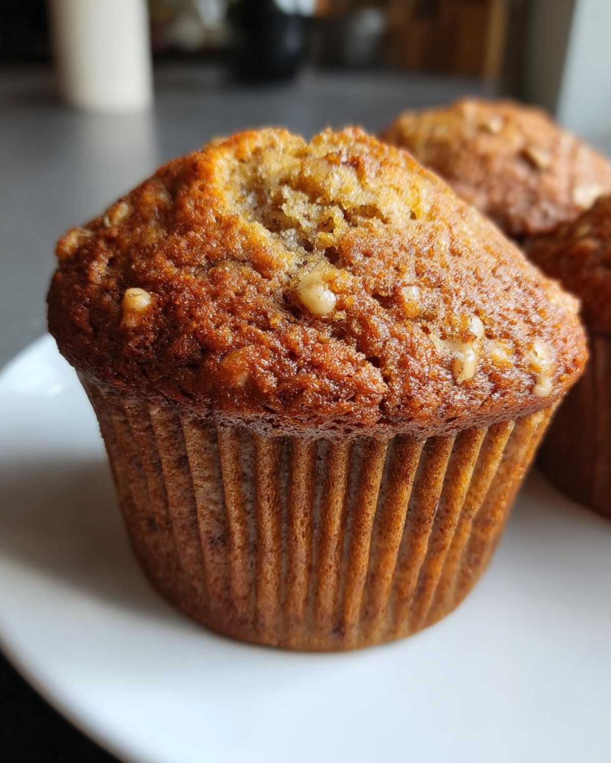 Close-up of a perfectly baked banana nut muffin with visible walnuts on the golden brown top.