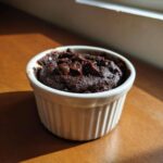 A rich, dark Cottage Cheese Microwave Brownie topped with chocolate chips in a white ramekin.