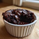 A rich, dark chocolate Cottage Cheese Microwave Brownie served warm in a white ramekin with melted chocolate chips.