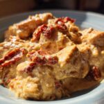 Close-up of creamy crockpot marry me chicken chunks topped with vibrant sun-dried tomatoes.