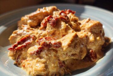 Close-up of creamy crockpot marry me chicken chunks topped with vibrant sun-dried tomatoes.