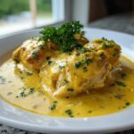 Three pieces of creamy lemon chicken smothered in a rich, yellow sauce and garnished with fresh parsley.