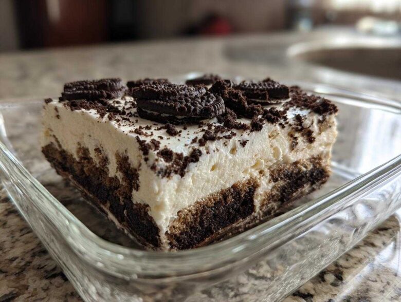 A close-up view of a generous slice of creamy oreo dirt cake topped with crushed cookies.