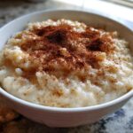 Close-up of a bowl of creamy rice pudding recipe generously sprinkled with ground cinnamon.