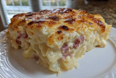 A close-up of a rich, creamy slice of scalloped potatoes and ham with a golden-brown, cheesy top.
