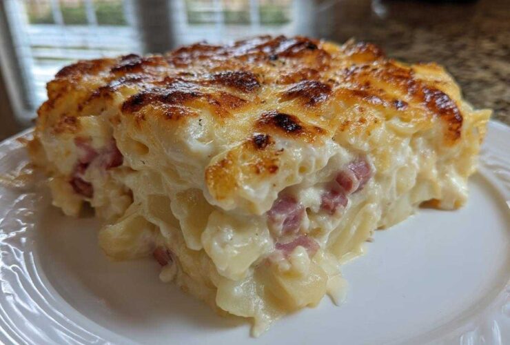 A close-up of a rich, creamy slice of scalloped potatoes and ham with a golden-brown, cheesy top.