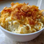 A close-up of a serving of creamy Tuna Casserole topped generously with golden, crispy cornflakes.