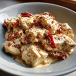 Close-up of tender chicken pieces smothered in a creamy sauce with sun-dried tomatoes, perfect for crockpot marry me chicken.