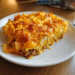 A close-up of a hearty slice of Dorito Casserole with a crunchy topping and cheesy, meaty layers.