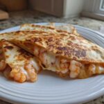 Close-up of a perfectly grilled shrimp quesadilla cut into wedges, showing melted cheese and seasoned shrimp spilling out.