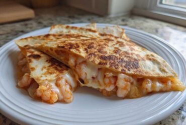 Close-up of a perfectly grilled shrimp quesadilla cut into wedges, showing melted cheese and seasoned shrimp spilling out.
