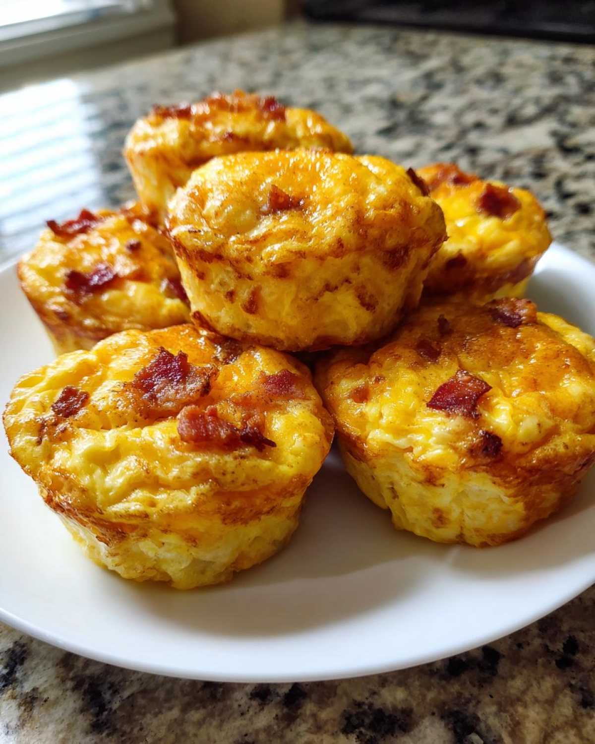 A stack of fluffy, golden brown bacon egg bites served on a small white plate.
