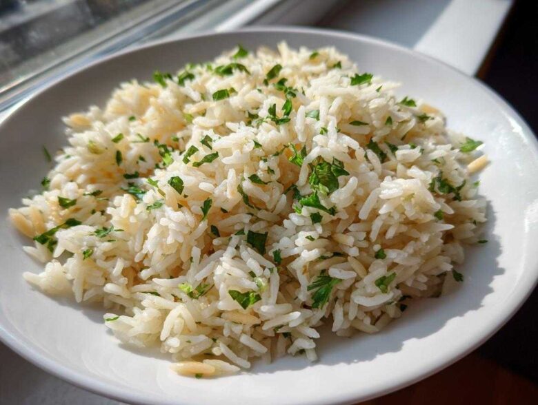 A close-up of fluffy rice pilaf garnished with fresh chopped parsley in a white bowl.