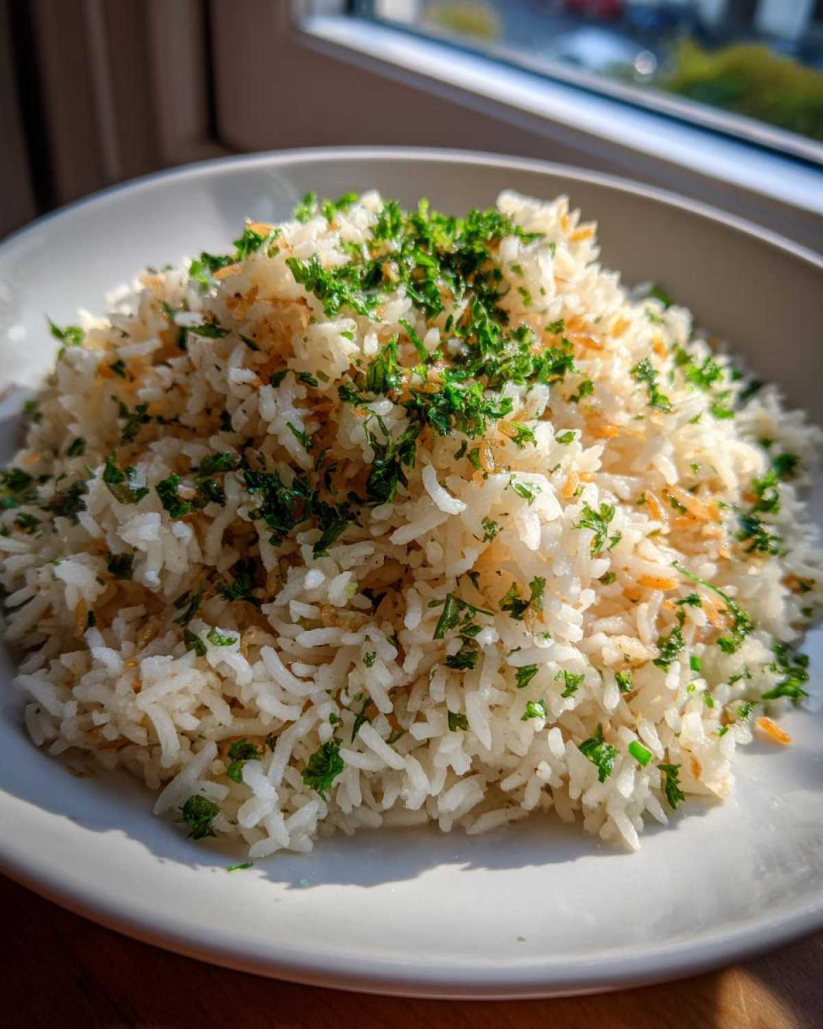 A close-up of fluffy rice pilaf, garnished with chopped parsley and toasted vermicelli pieces.