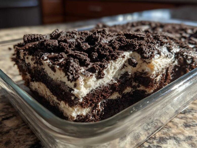 Close-up of a rich, layered slice of dirt cake featuring dark chocolate cake, white cream filling, and crushed cookie topping.