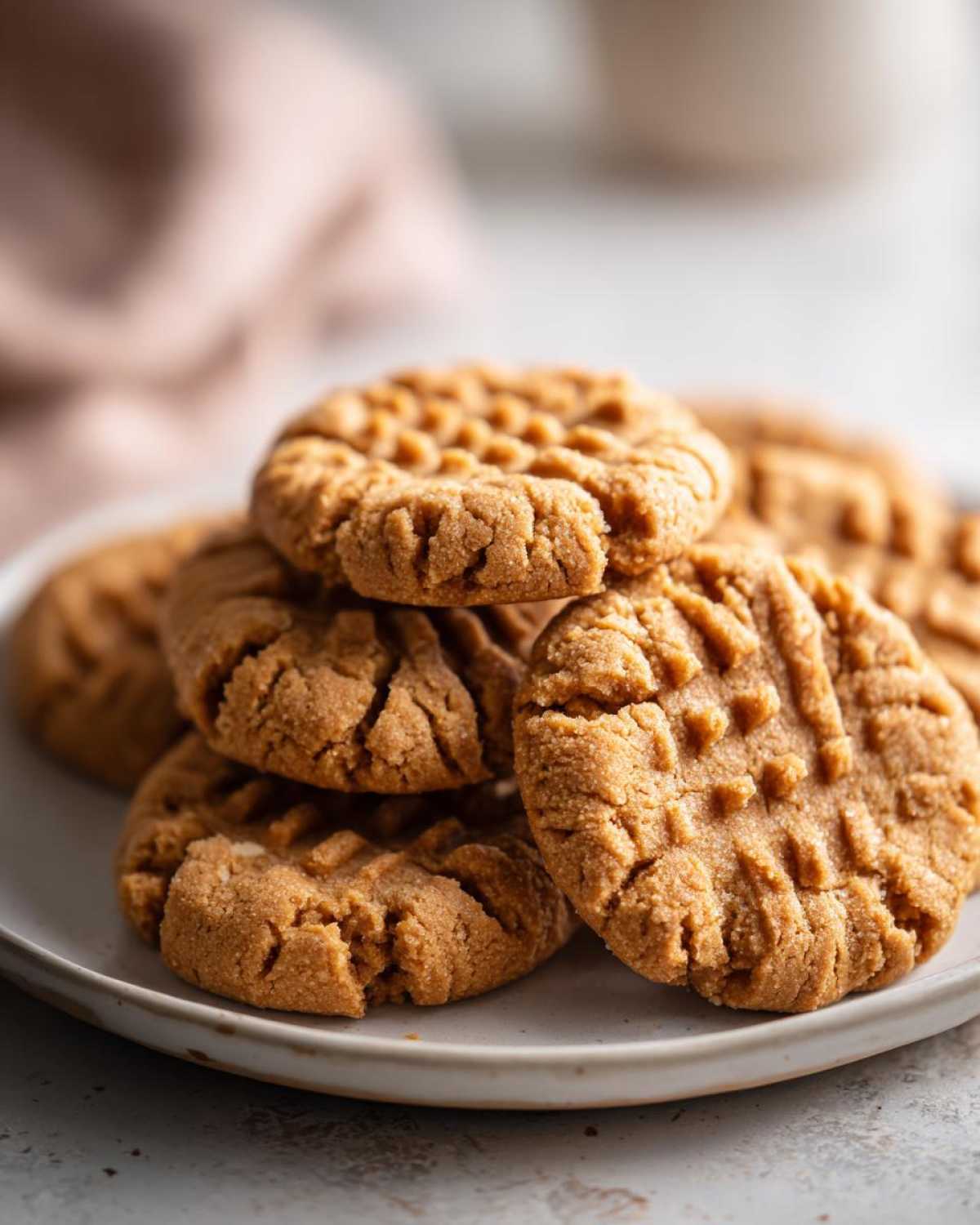 Close-up of a stack of freshly baked peanut butter cookies showing the classic criss-cross fork pattern.