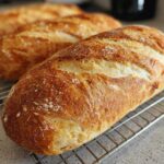 Close-up of a golden-brown, crusty loaf of french bread cooling on a wire rack.