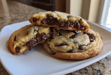 Close-up of homemade chocolate chip cookies, one broken open showing a molten, gooey chocolate center.