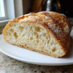 Close-up of a freshly baked italian bread slice showing an open, airy crumb and golden, dusted crust.