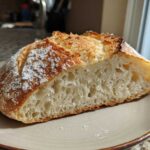 A close-up of a slice of amazing italian bread showing an airy crumb structure and golden, dusted crust.