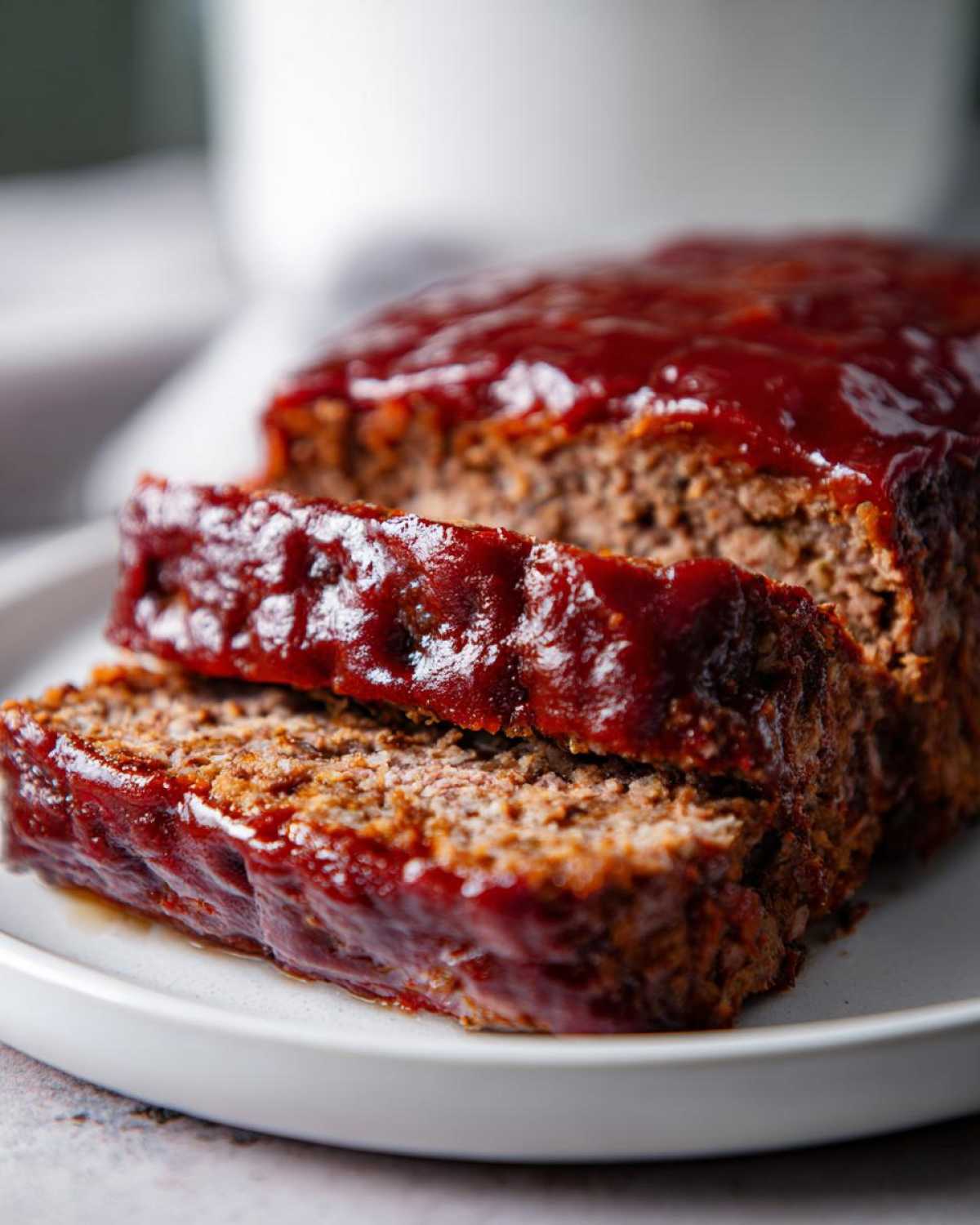 Close-up of two thick slices of juicy Keto meatloaf covered in a rich, glossy red glaze.