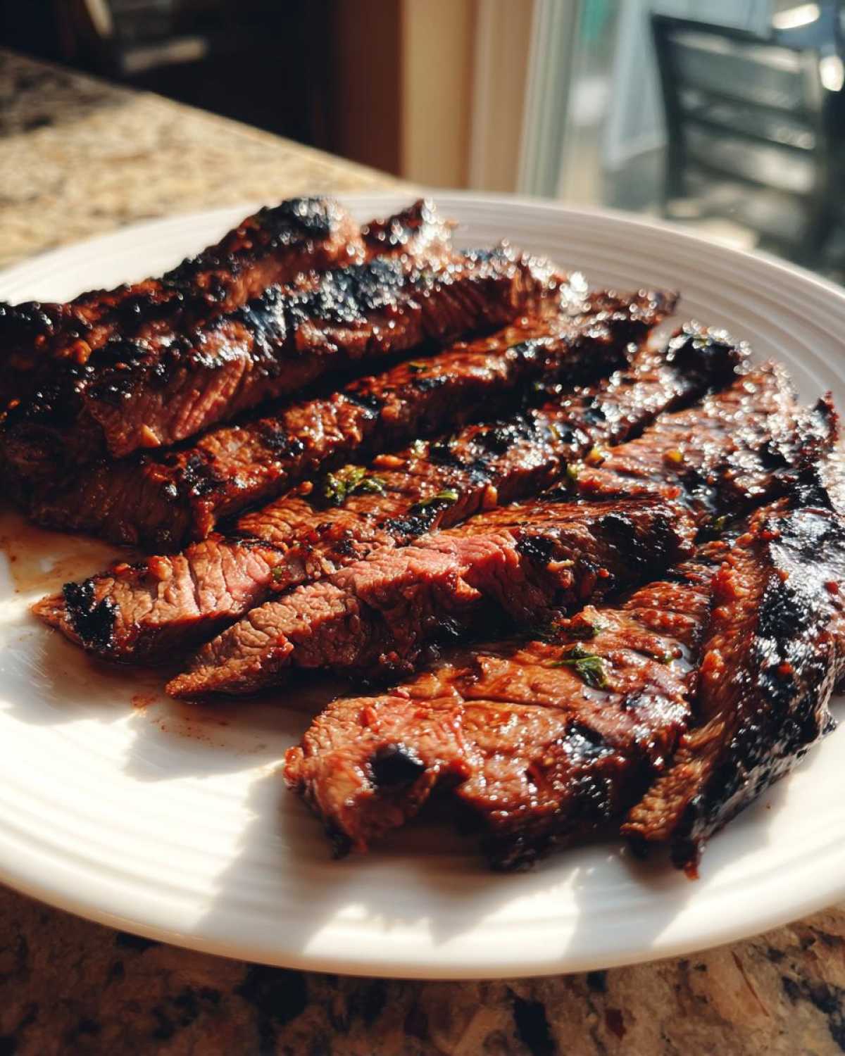 Slices of perfectly grilled steak showing a medium-rare center, coated in a rich Carne asada marinade.