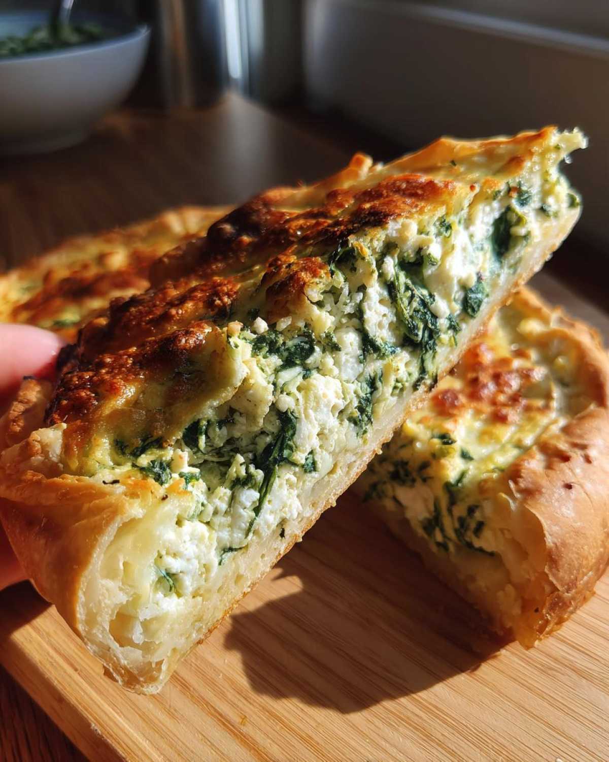 A close-up of two slices of Mediterranean Spinach and Feta Cheese Crisps showing the flaky crust and rich filling.