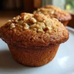 Close-up of a perfectly baked banana nut muffin with a golden-brown top sprinkled with chopped nuts.