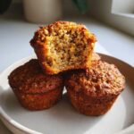 Close-up of three moist bran muffins, one split open showing the textured, wholesome interior.