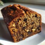 Close-up of a freshly baked, moist date nut bread loaf showing visible dates and walnuts.