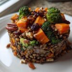 A beautifully molded serving of veggie lentil salad featuring lentils, orange sweet potato, green broccoli florets, pecans, and dried cranberries.