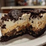 Cross-section of a rich peanut butter pie featuring a thick Oreo crust, creamy peanut butter layer, and whipped topping, garnished with Oreos.