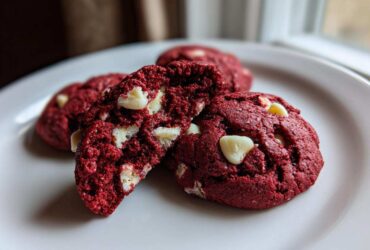 Close-up of soft, vibrant red velvet cake mix cookies with white chocolate chips on a white plate.
