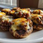 A plate of perfectly baked sausage stuffed mushrooms topped with golden, melted cheese.