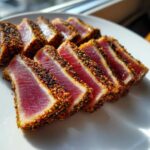 Slices of perfectly Seared Ahi Tuna, crusted with sesame seeds, showing a rare red center.