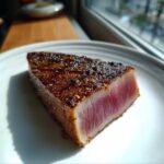 A perfectly seared tuna steak, rare in the center, showcasing a dark, seasoned crust from the MARINADE FOR TUNA STEAK.