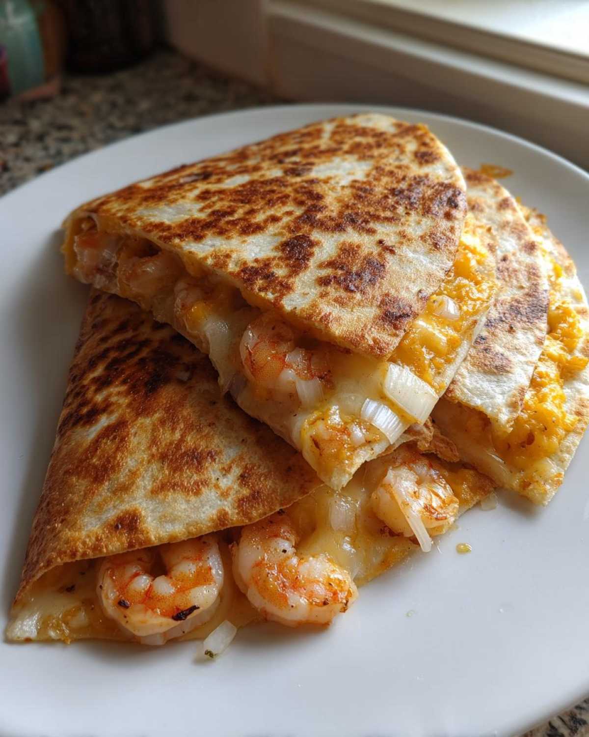 Close-up of golden brown shrimp quesadilla wedges filled with melted cheese and plump shrimp.