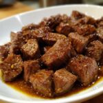 Close-up of tender, bite-sized pieces of crockpot steak glistening in a rich, savory brown sauce.