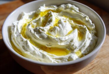 Close-up of creamy, bright white whipped feta dip topped generously with golden olive oil.