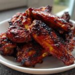 A close-up of a white bowl filled with crispy, glazed Air Fryer BBQ Chicken Wings.