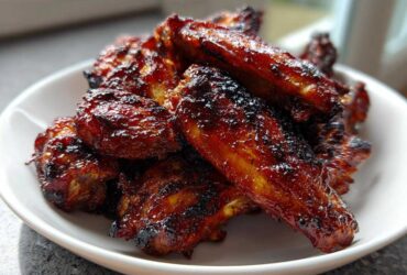 A close-up of a white bowl filled with crispy, glazed Air Fryer BBQ Chicken Wings.