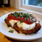 Close-up of a crispy Air Fryer Chicken Parmesan topped with melted mozzarella, marinara sauce, and fresh basil.