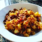 Close-up of golden brown, crispy Air Fryer Corned Beef Hash with chunks of potato and meat in a white bowl.