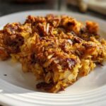 A close-up of a serving of golden brown, crispy Air Fryer Corned Beef Hash with Potatoes on a white plate.