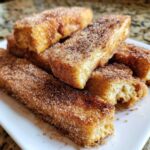 Close-up of several golden Air Fryer French Toast Sticks generously coated in cinnamon sugar.