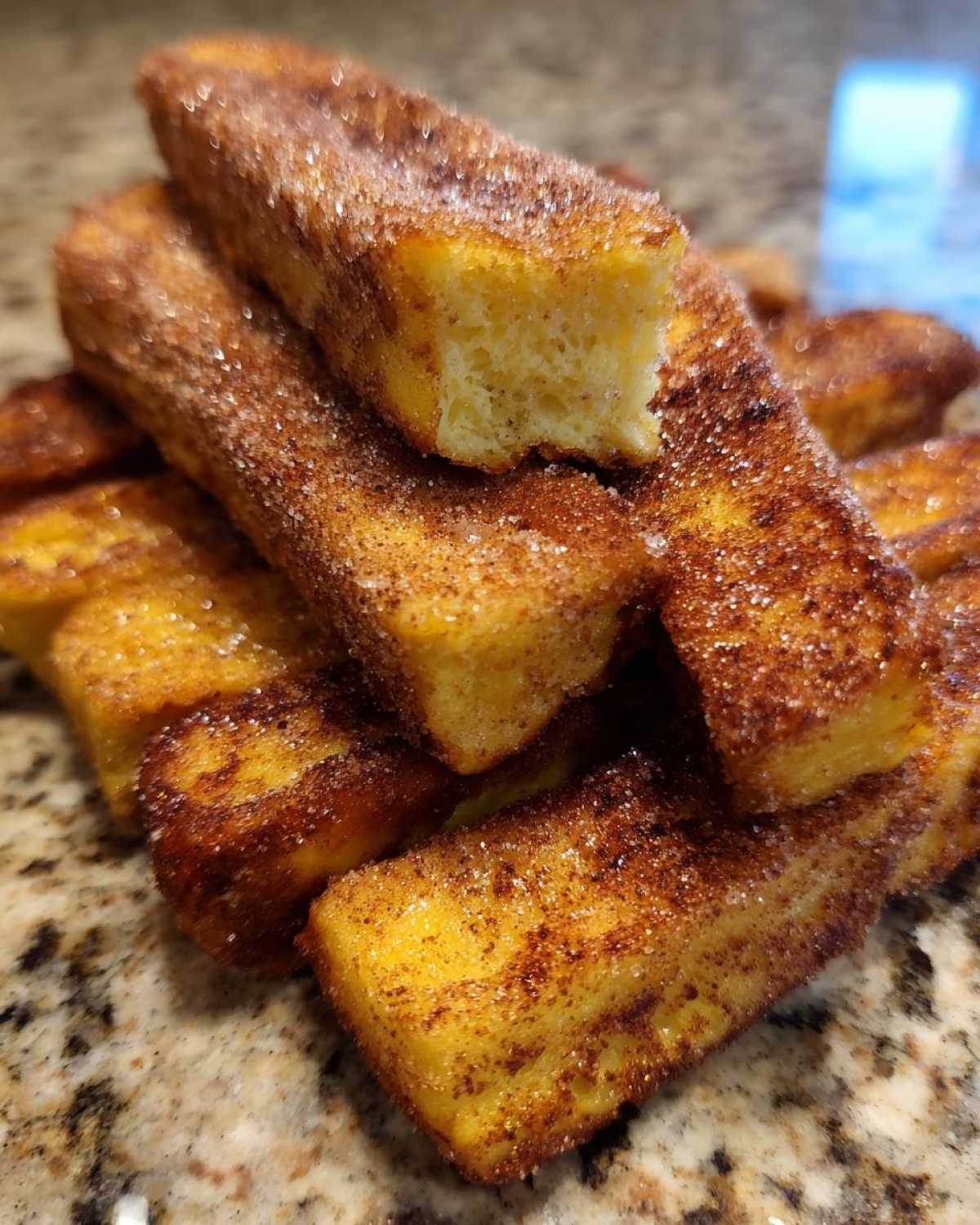 Close-up of golden Air Fryer French Toast Sticks piled high and coated generously with cinnamon sugar.